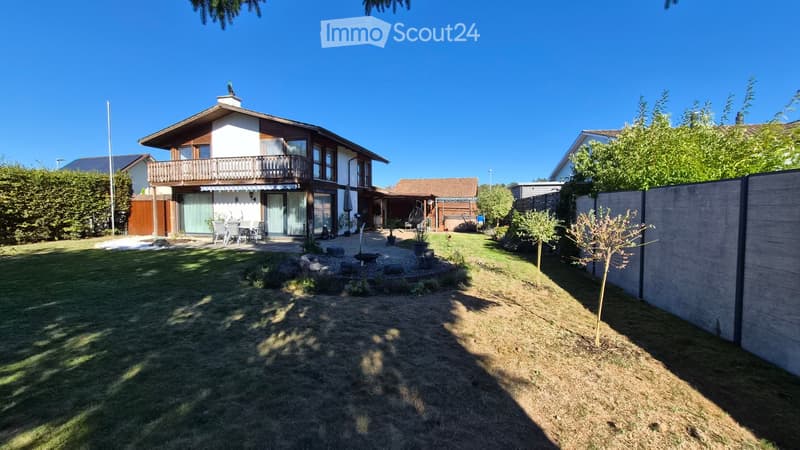 Well-maintained garden with a patio area, outdoor seating, small water feature, and surrounding greenery.