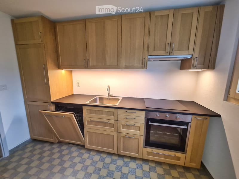 Compact kitchen with light wooden cabinets, a sink, a faucet, and an oven, featuring a tiled floor and modern design.