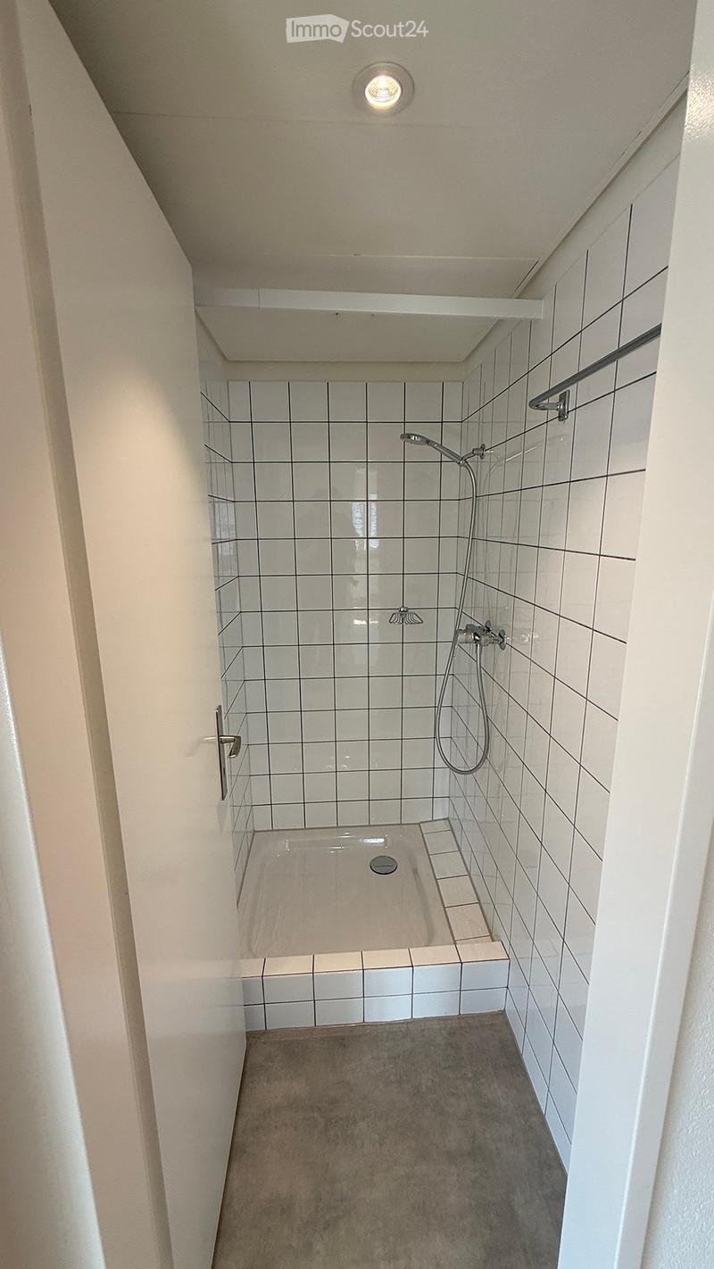Modern shower area with white tiled walls, a built-in seat, and a handheld showerhead.