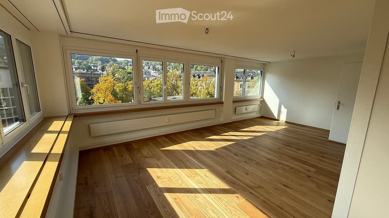Empty room with wooden flooring, large windows, and radiators. No furniture or equipment present.