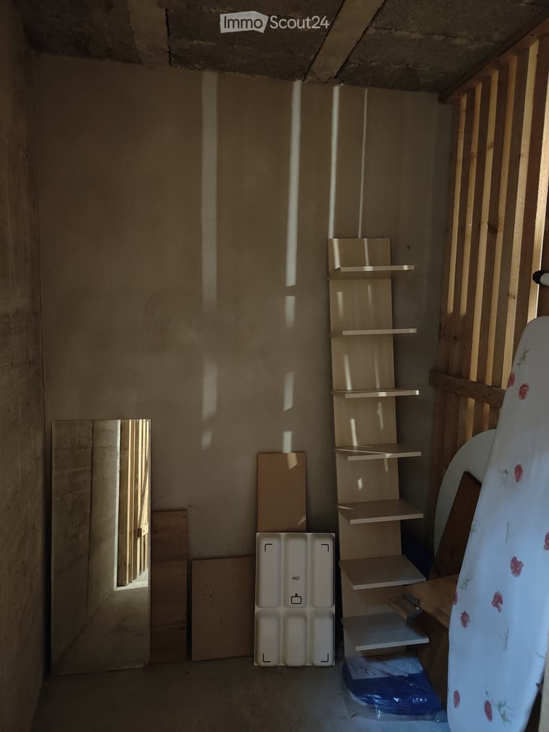 Empty room with unfinished wooden shelves, exposed wooden beams, and a partially visible door frame. No furniture or personal items are present.