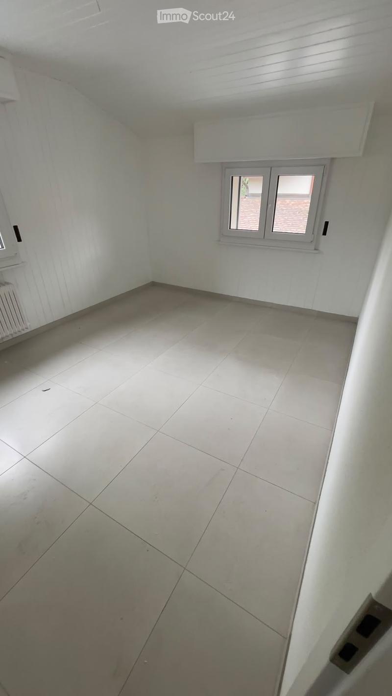 Empty room with white walls, tiled floor, and a window with white frame. No furniture or equipment present.