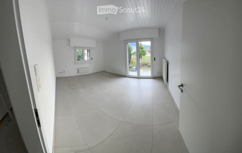 Empty room with white walls, tiled floor, and large sliding glass door leading to a balcony or outdoor area.