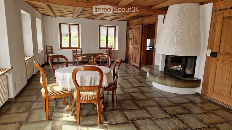 Cozy dining area with wooden chairs, a round table, and a prominent stone fireplace.