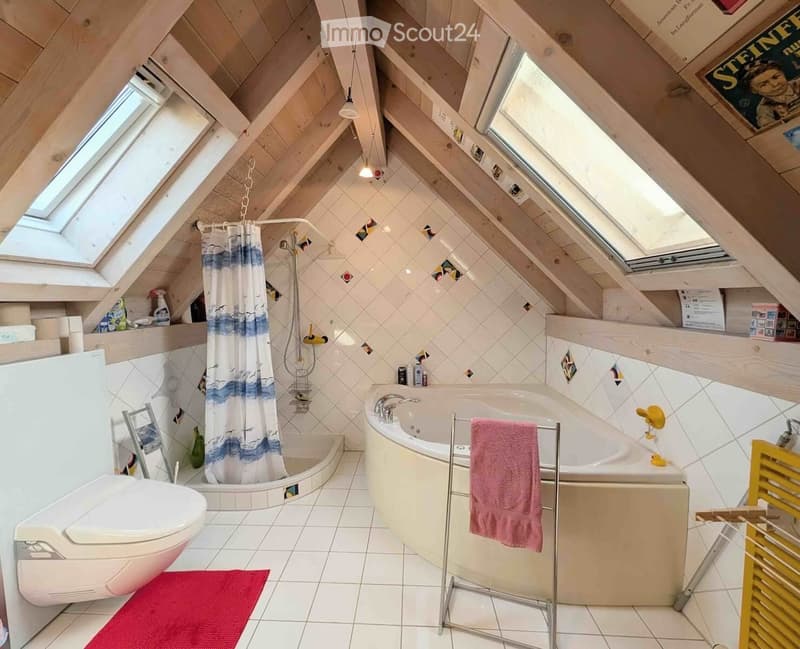 Bright attic bathroom with skylights, featuring a bathtub, toilet, shower area with a curtain, and shelves holding cleaning supplies.