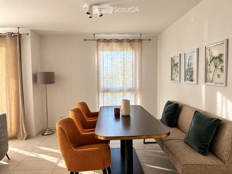 Living room with a sofa, wooden table, chairs, vase, floor lamp, and picture frames on the wall.