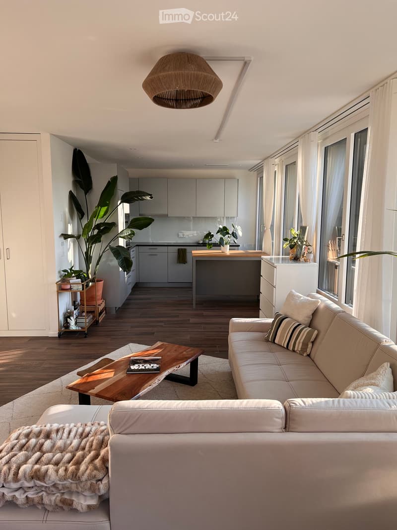 living room with white leather sofa, large windows with white curtains, wooden floor, coffee table, and wooden ceiling lamp