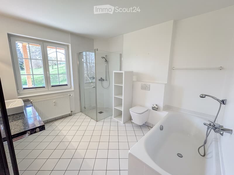 Modern bathroom with white tiles, a bathtub, toilet, glass-enclosed shower, and a small shelf unit.