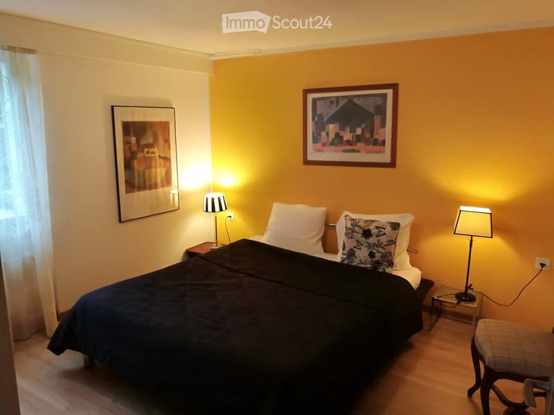 Cozy bedroom with a double bed, nightstands, lamps, and artwork on the walls.