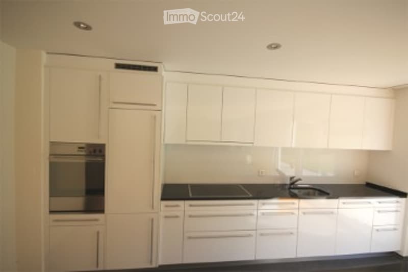 Modern kitchen with white cabinets, black countertops, and built-in appliances.