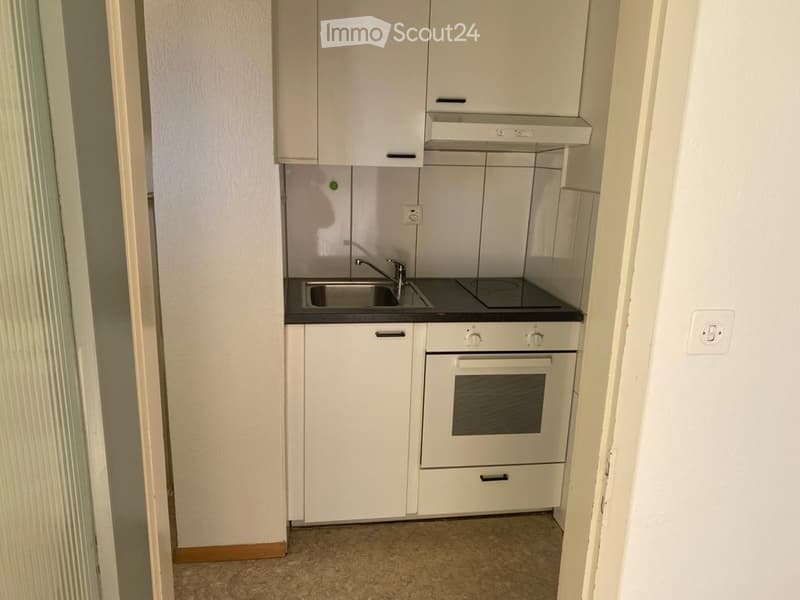 Compact kitchen with white cabinets, a sink, a faucet, and a built-in oven.