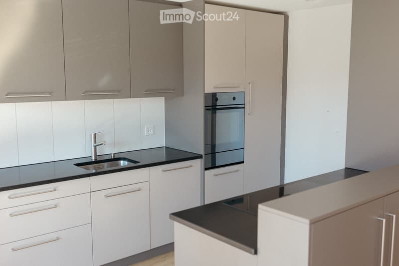 Modern kitchen with white cabinets, black countertops, a stainless steel sink, and a built-in oven.