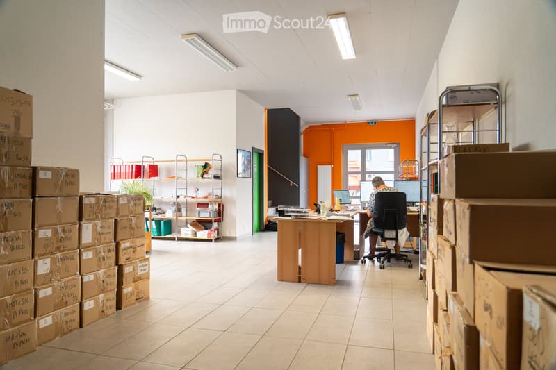Office space with a desk, chair, computer, shelves, and boxes stacked around the room.