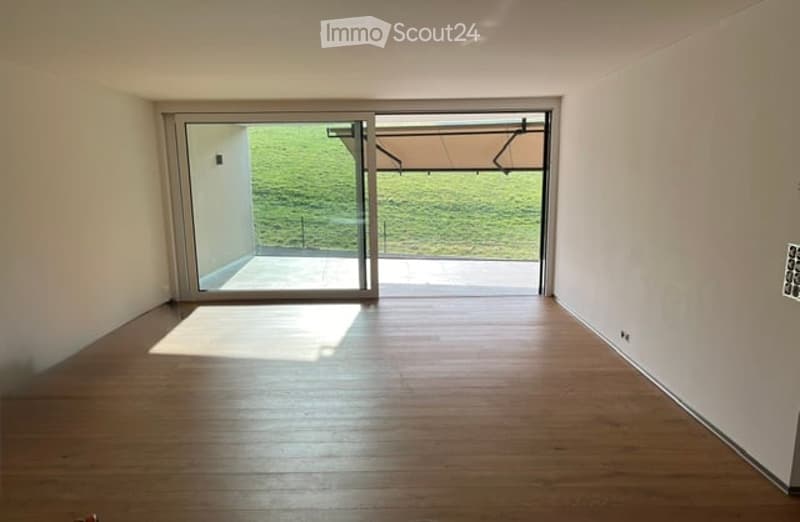 Empty room with wooden flooring and large sliding glass doors leading to an outdoor area.