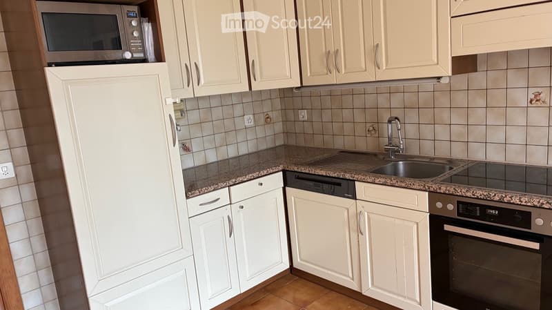 Modern kitchen with white cabinets, granite countertops, stainless steel appliances, and a sink with a faucet.