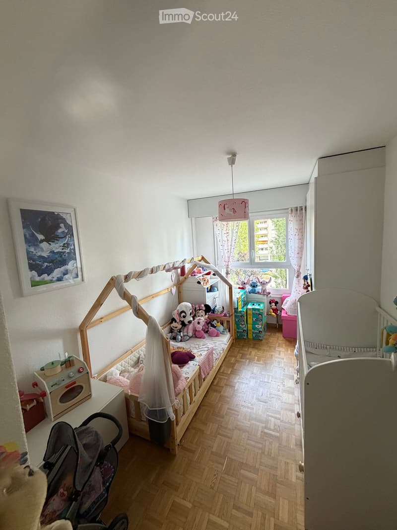 A child's bedroom with a wooden toy bed, a toy stove, a toy crib, and various toys and decorations.