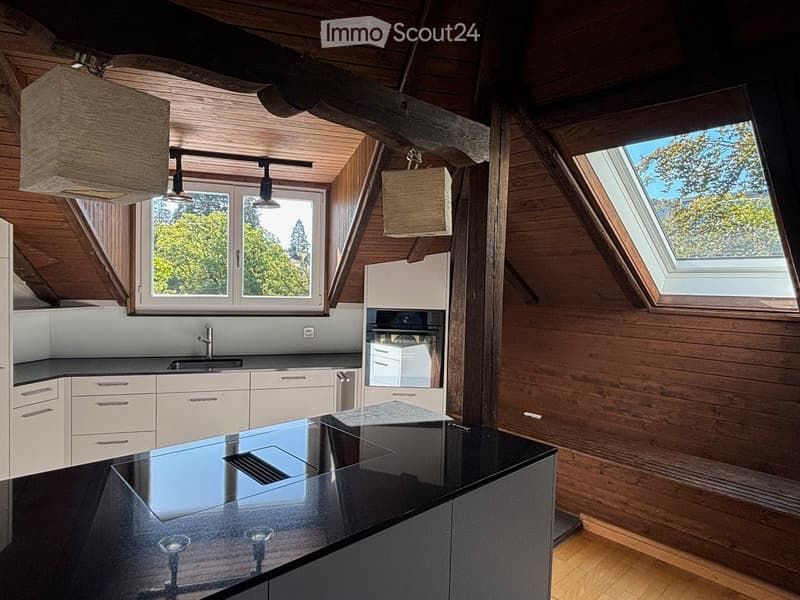 Modern kitchen with wooden walls, white cabinets, black countertop, and built-in appliances, including an oven and sink.