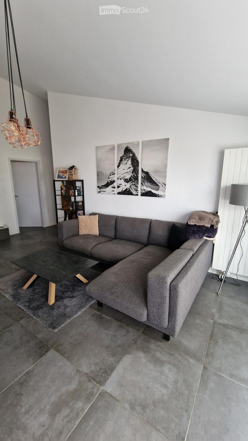 Modern living room with a grey sectional sofa, glass coffee table, floor lamp, and decorative wall art.