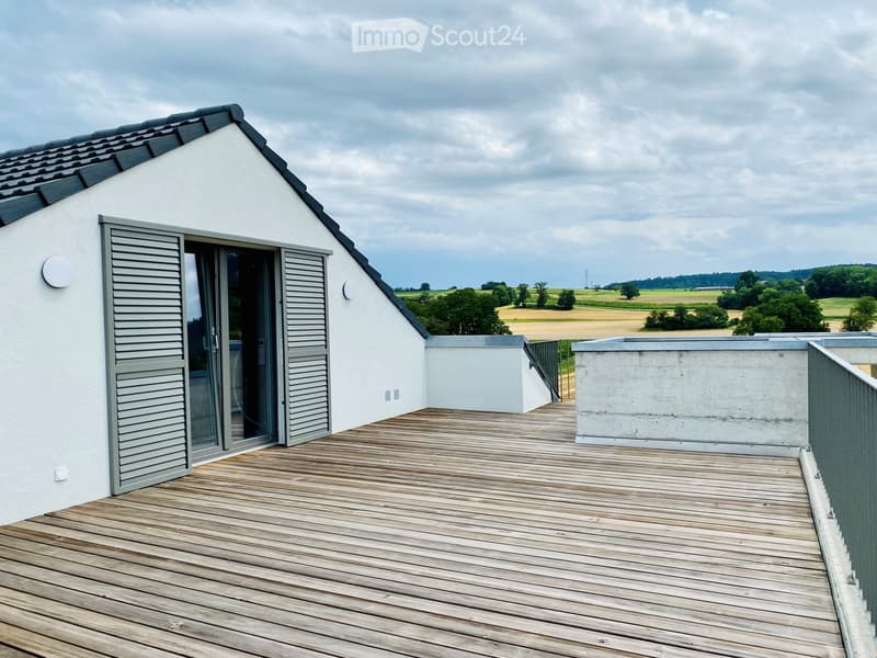 Building. Balcony with wooden deck, glass door, metal railing, wide open view of countryside