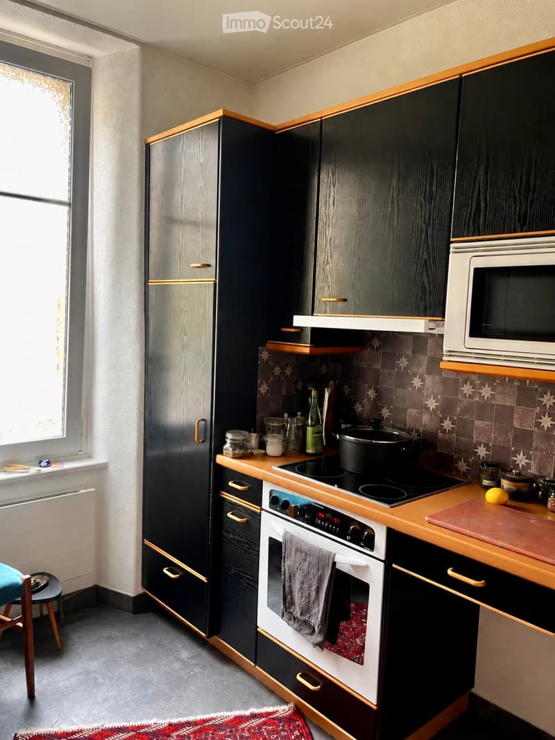 Modern kitchen with dark wooden cabinets, stainless steel appliances, and a wooden countertop. Features include a refrigerator, oven, microwave, stove, and various kitchen items on the counter.