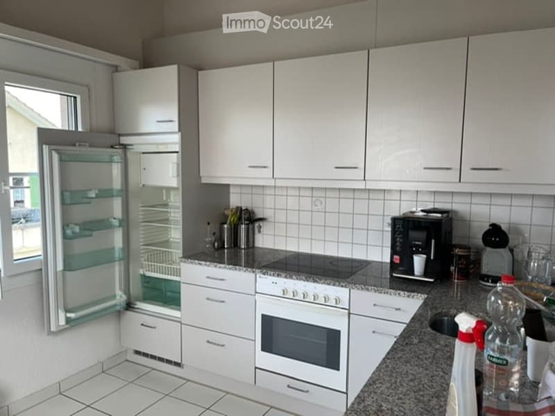 Modern kitchen with white cabinets, granite countertop, stainless steel appliances, and a large window.