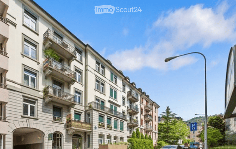 Multi-story residential building with balconies, large windows, and decorative facades.