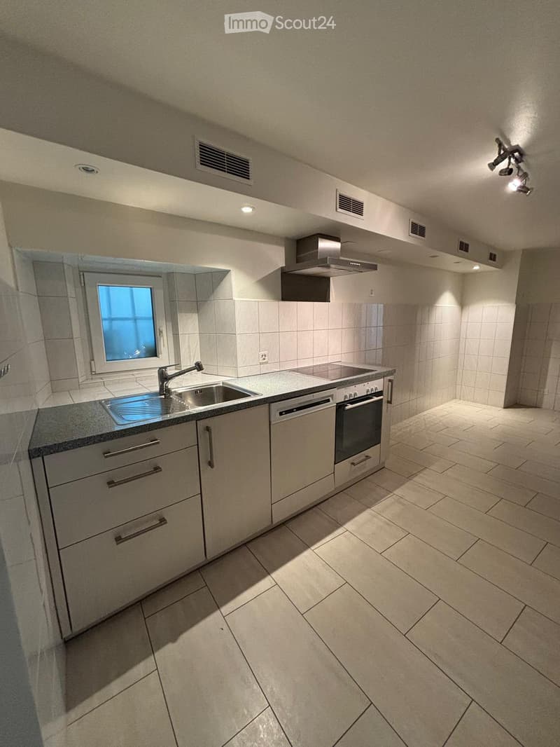 Modern kitchen with light-colored cabinets, a sink, oven, dishwasher, and a window letting in natural light.