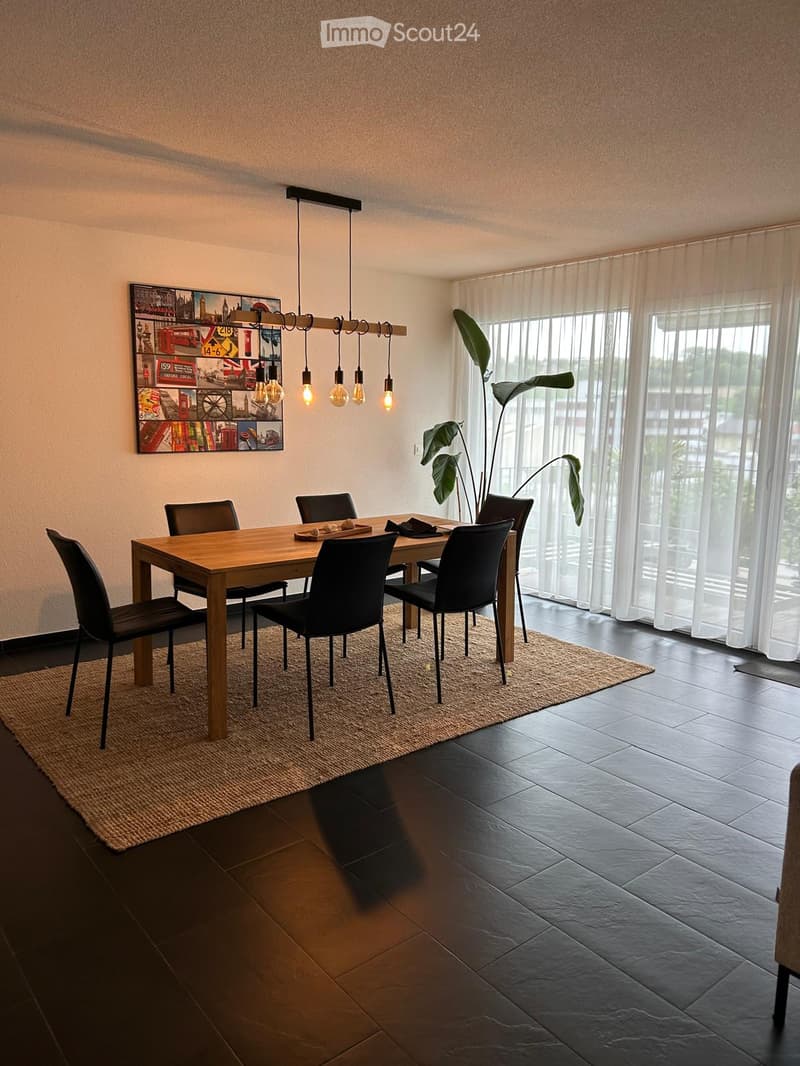 {"visible_features": ["Balcony / Terrace"],"type": "Dining room","description": "Spacious dining room with a wooden dining table and black chairs, a large artwork on the wall, and a hanging light fixture. The room has large windows that provide natural li