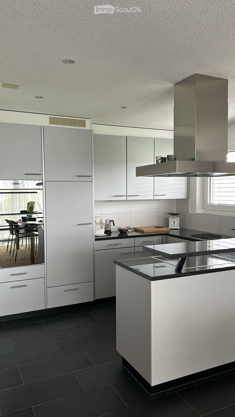 Modern, minimalist kitchen with white cabinets, stainless steel appliances, and black granite countertops. The kitchen features a dishwasher and an island with additional counter space.