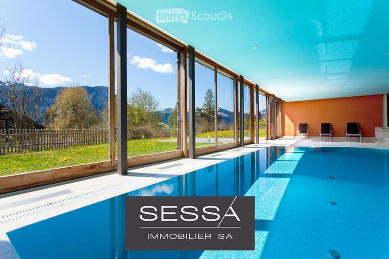 Outdoor area featuring a swimming pool with a modern design, large glass windows, and a scenic mountain view. There are three black chairs near the pool area.