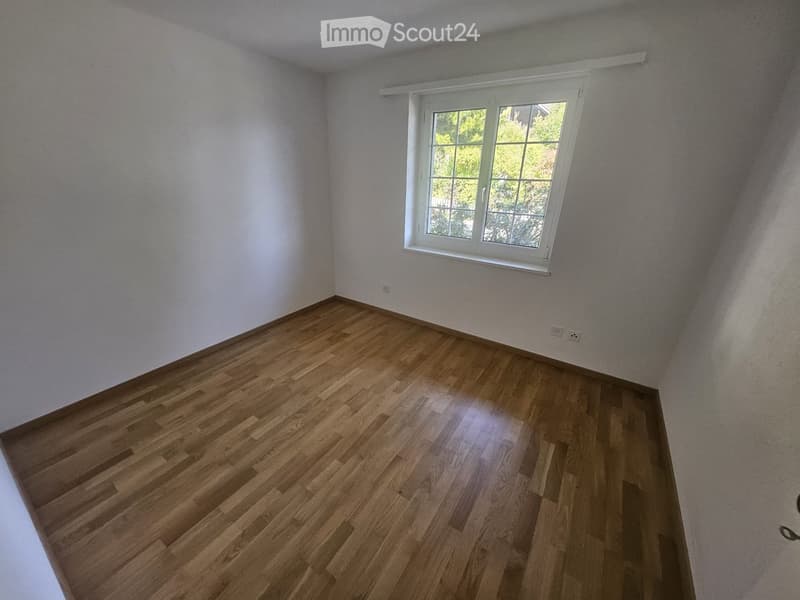 Empty room with wooden flooring and white walls, featuring a single window with white frame and multiple panes.