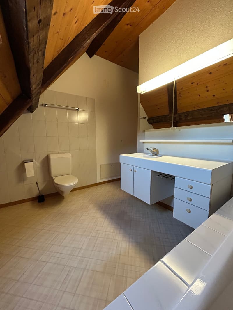 Modern bathroom with a toilet, sink, and cabinet, featuring a sleek design and warm lighting.