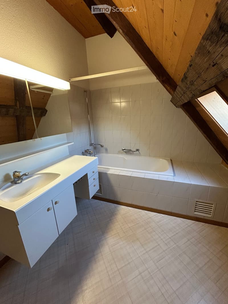 Bathroom with a white sink, bathtub, and built-in cabinets. The room features exposed wooden beams and a skylight window providing natural light.