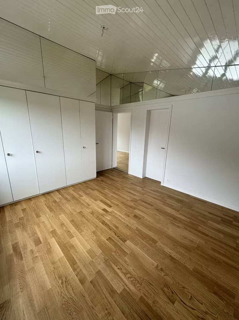 Completely empty room with light wooden flooring, white walls, and built-in white cabinets. No furniture or equipment present.