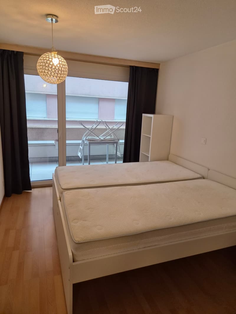 Bedroom with a double bed, a small shelf, and a balcony with a table and chairs.
