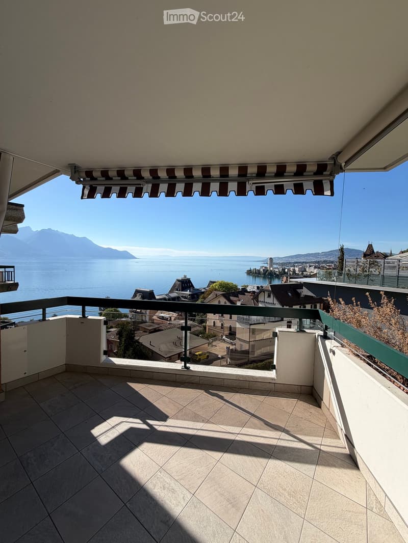 Balcony with tiled floor, metal railing, and scenic view of a lake and mountains.