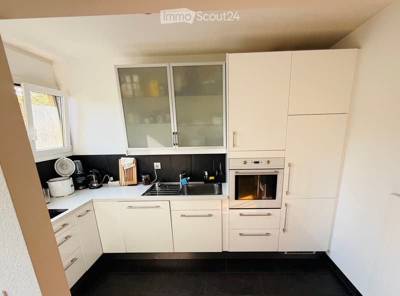 Modern kitchen with white cabinets, stainless steel appliances, and black countertops.