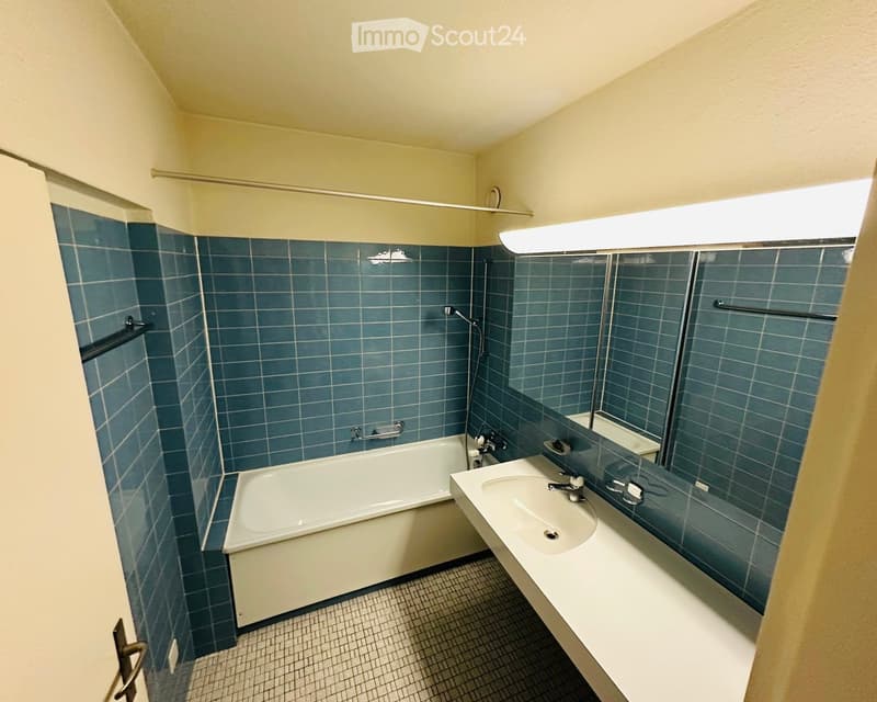Bathroom with blue tiled walls, a bathtub, a sink with a mirror, and a shower stall with a glass enclosure.