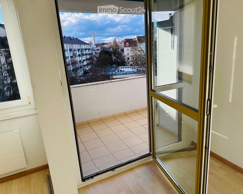Balcony with tiled floor, glass sliding doors, and a view of the cityscape.