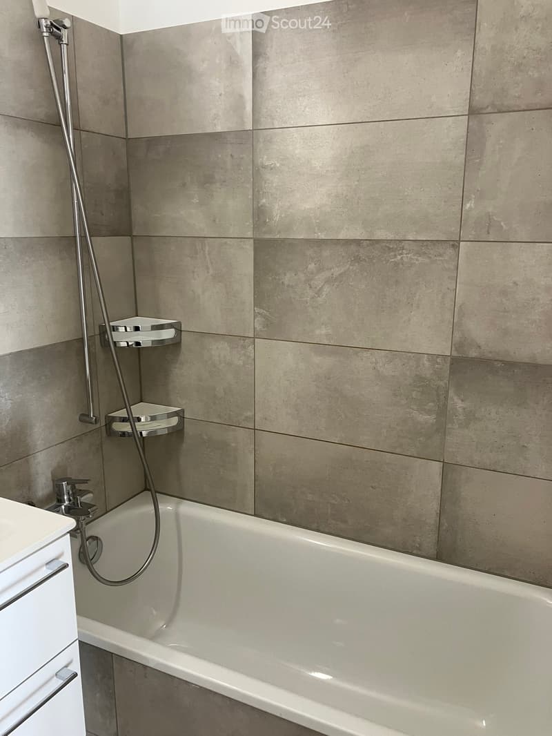 Modern bathroom with a bathtub, chrome showerhead, and built-in shower shelves.