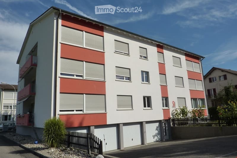 3-story building, white exterior, red accents, balconies, garage entrance