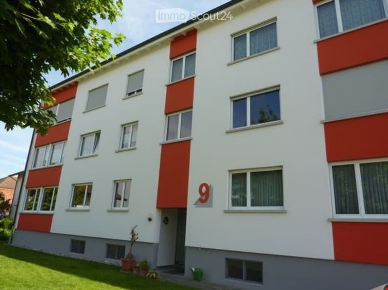 Three story building with red and white accents, multiple windows and a grassy lawn in front