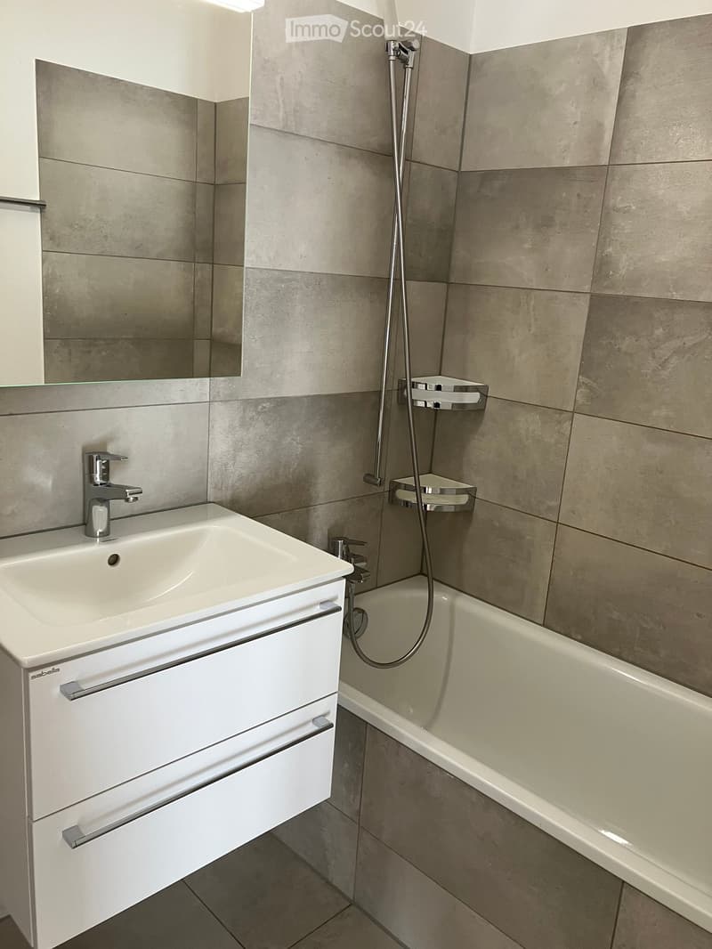 Modern bathroom with a white sink, bathtub, and chrome fixtures.