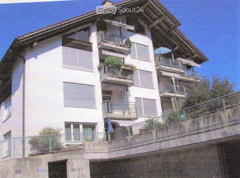 Multi-story residential building with balconies, large windows, and a modern design.
