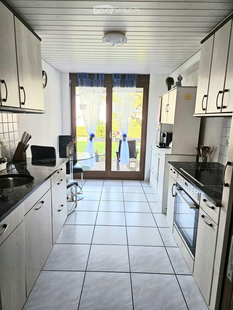 Modern kitchen with white cabinets, stainless steel appliances, and a large sliding glass door leading to a patio.
