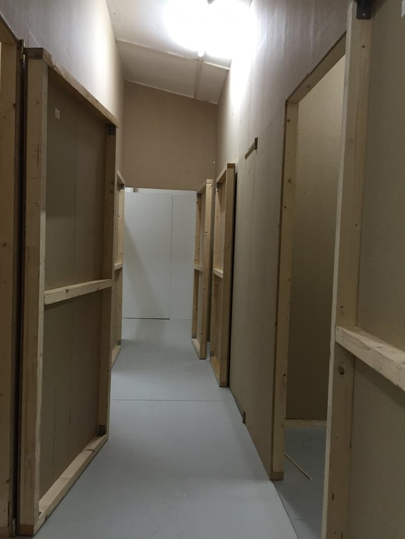 Empty hallway with wooden paneling and doors, featuring a smooth blue floor and white walls.
