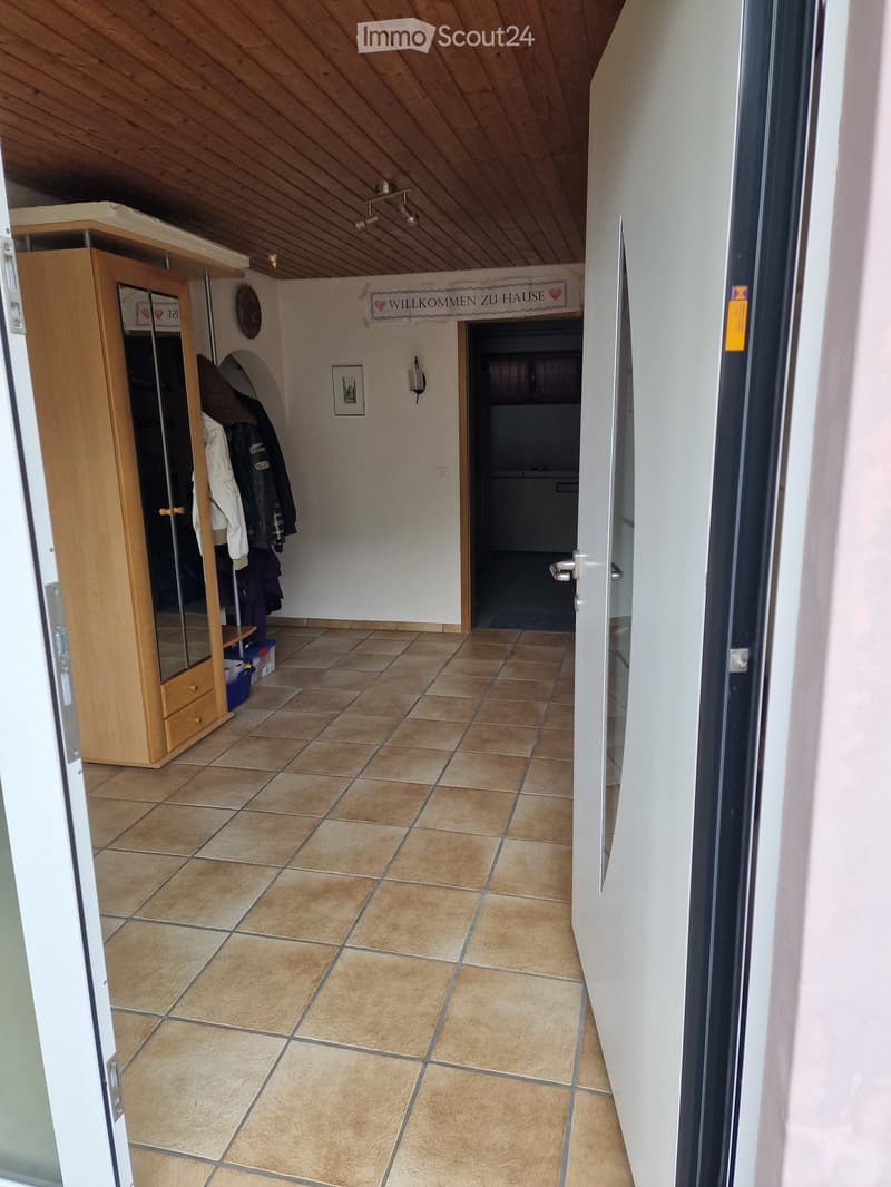 Hallway with tiled floor, wooden coat closet, and a sign that reads "WILLKOMMEN ZU HAUSE".