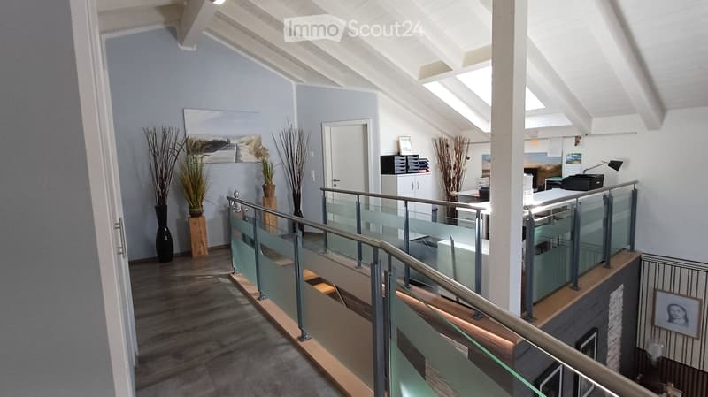 Modern hallway with glass railing, wooden flooring, and decorative vases. Features a raised ground floor and ample natural light from skylights.