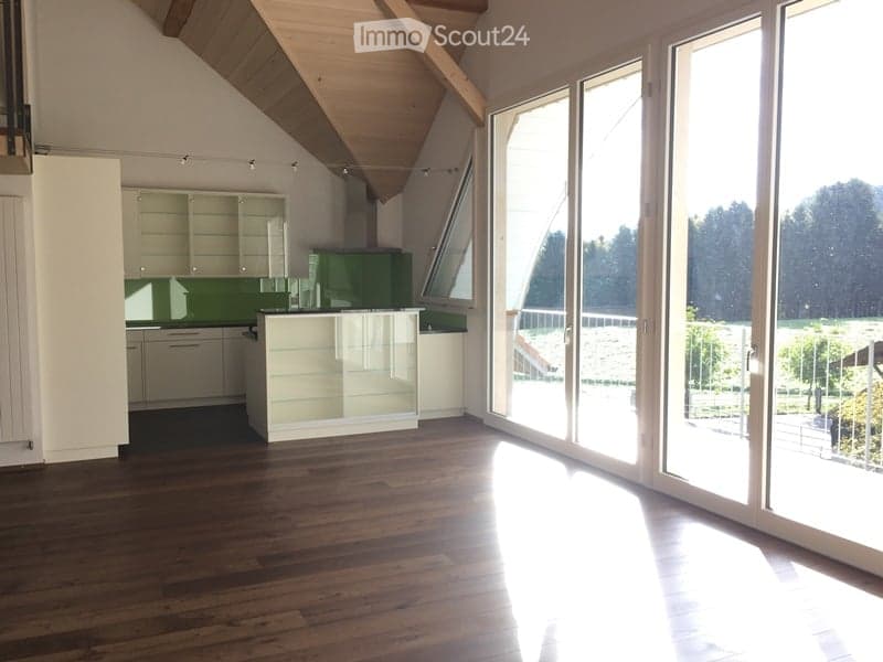 Bright, modern kitchen with white cabinets, green accents, and large windows offering a scenic view of the outdoors.