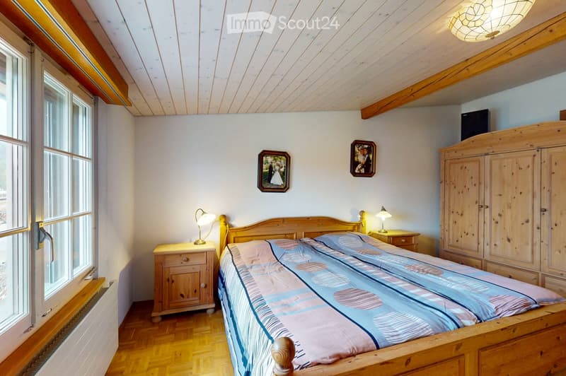 Cozy bedroom with wooden bed, nightstands, lamps, wardrobe, and framed pictures on the wall.